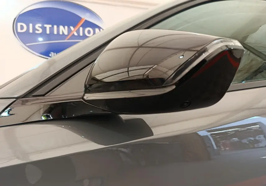 Rétroviseur droit gris foncé brillant de Peugeot 308 2026, reflet de l'intérieur du garage visible en arrière-plan.