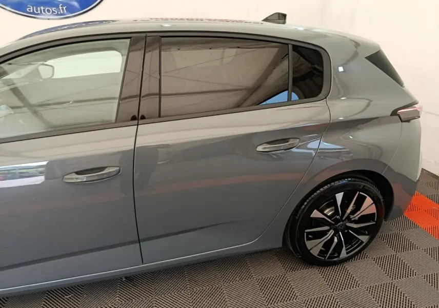 Vue latérale droite d'une Peugeot 308 gris foncé 2026, mettant en valeur les jantes noires et les vitres teintées.
