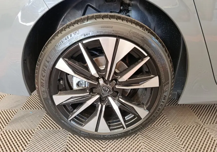 Gros plan sur la roue avant droite de la Peugeot 308 gris foncé, avec jante alliage noire et argentée au design moderne.