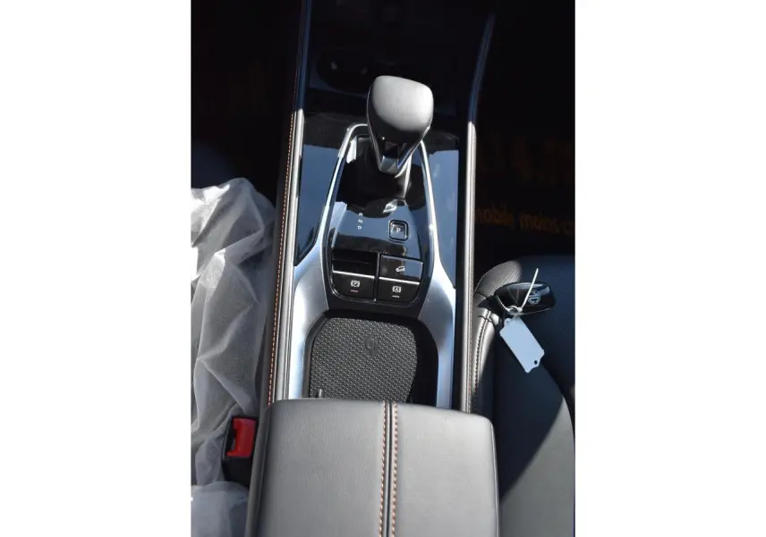 Vue plongeante sur la console centrale noire du MG Motor EHS 1.5 Hybrid+ avec levier de vitesses et chargeur à induction.
