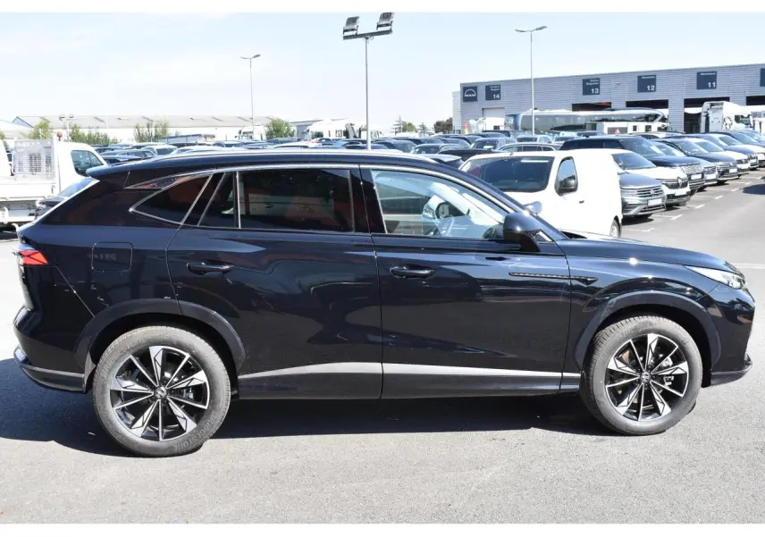 Vue latérale droite du SUV MG EHS noir métallisé avec jantes alliage 19 pouces sur parking extérieur.
