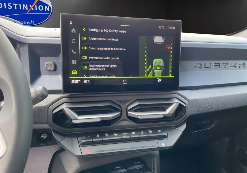 Tableau de bord du Dacia Duster hybride 2025 avec écran tactile affichant les aides à la conduite et aérateurs hexagonaux.