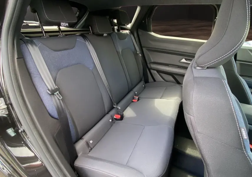Vue intérieure côté droit des sièges arrière en tissu noir et bleu du Dacia Duster hybride 2025 avec portes ouvertes.