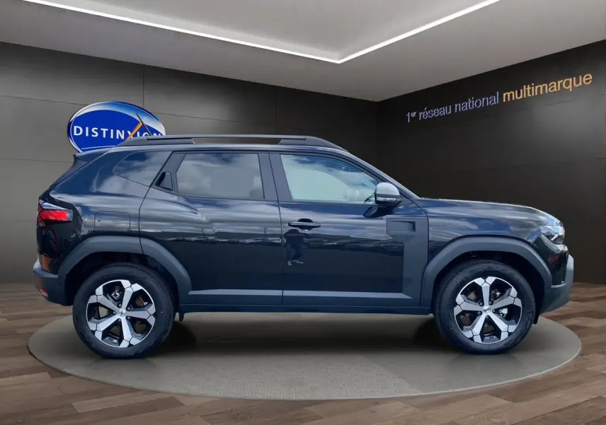 Profil côté gauche du Dacia Duster hybride noir 2025 avec jantes alliage et barres de toit visibles.