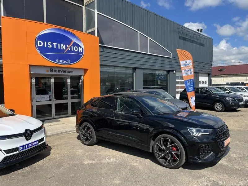 Audi RS Q3 Sportback noir Mythic vue 3/4 avant droit avec jantes noires et étriers rouges devant un garage Distinxion