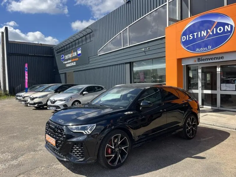 Audi RS Q3 Sportback noir Mythic vue 3/4 avant droit avec jantes sport et étriers rouges devant un concessionnaire