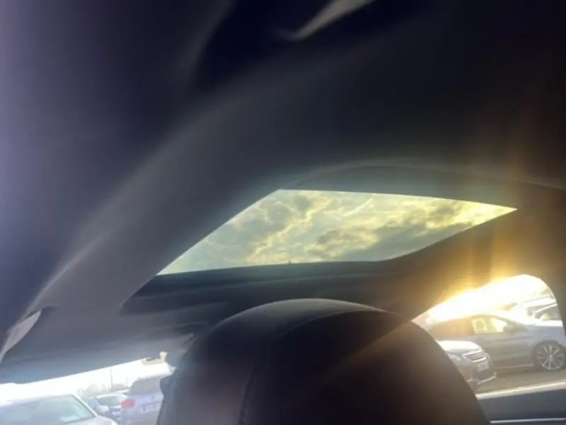 Vue intérieure du toit ouvrant panoramique d'une Audi RS Q3 Sportback Noir Mythic avec ciel nuageux visible.