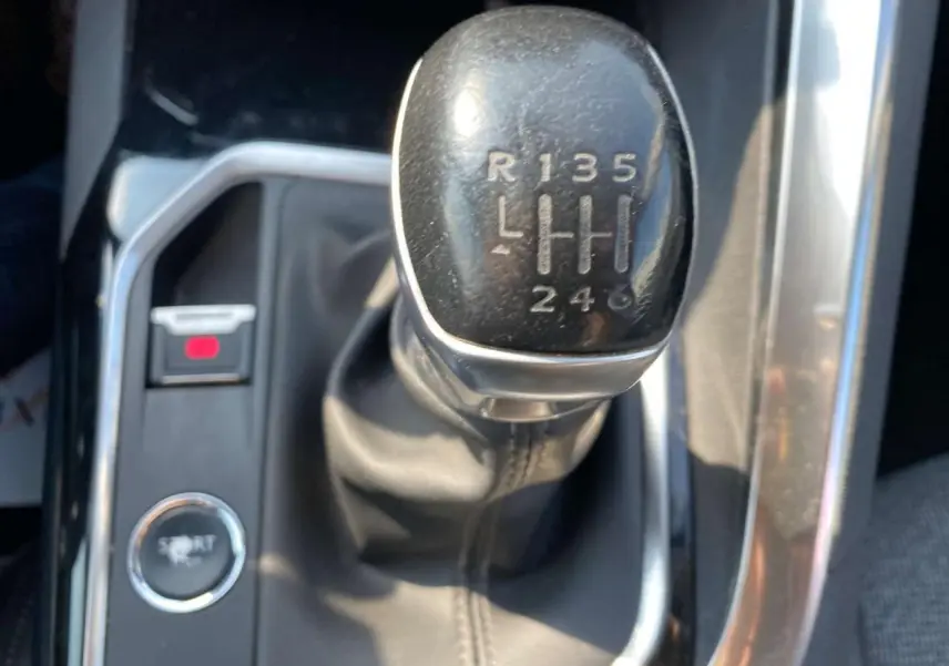 Gros plan sur le levier de vitesse manuel noir du Peugeot 3008 blanc, avec bouton mode Sport visible à gauche.