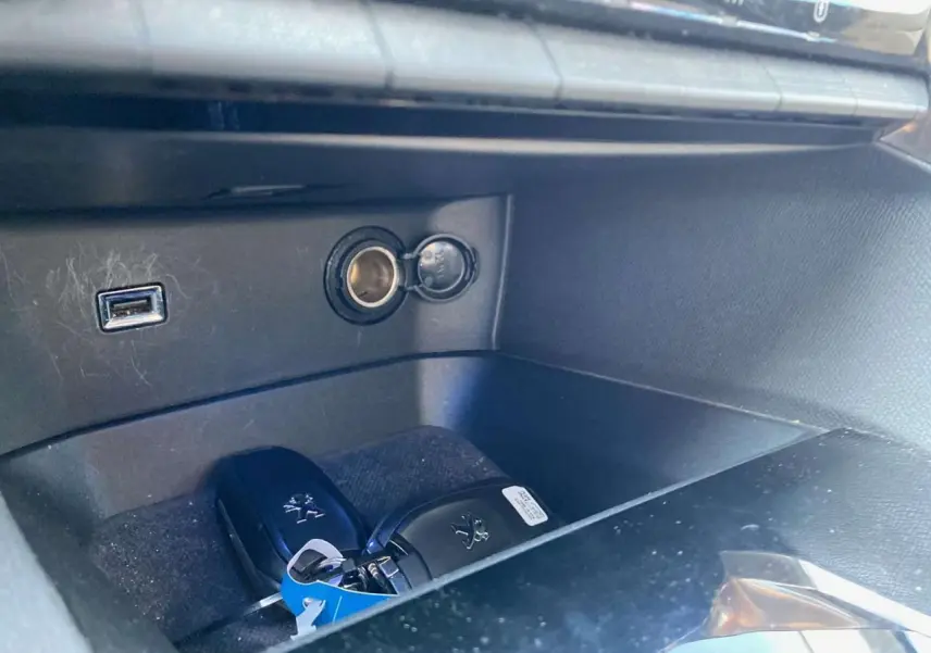 Gros plan sur la console centrale du Peugeot 3008 blanc avec clé mains libres et prise USB visible