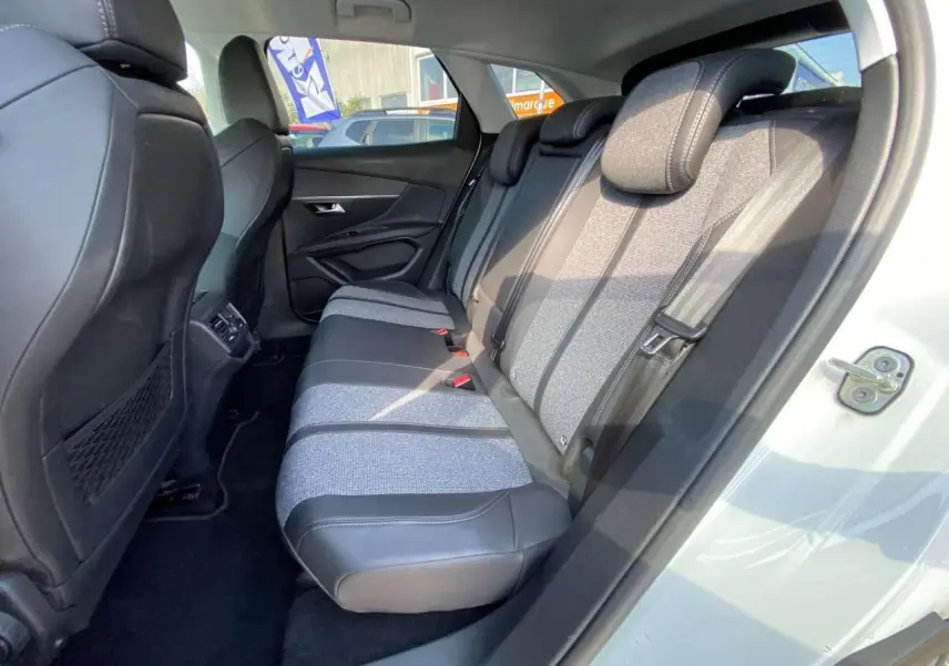 Vue intérieure côté droit montrant la banquette arrière bi-matière grise et noire du Peugeot 3008 blanc de 2018.