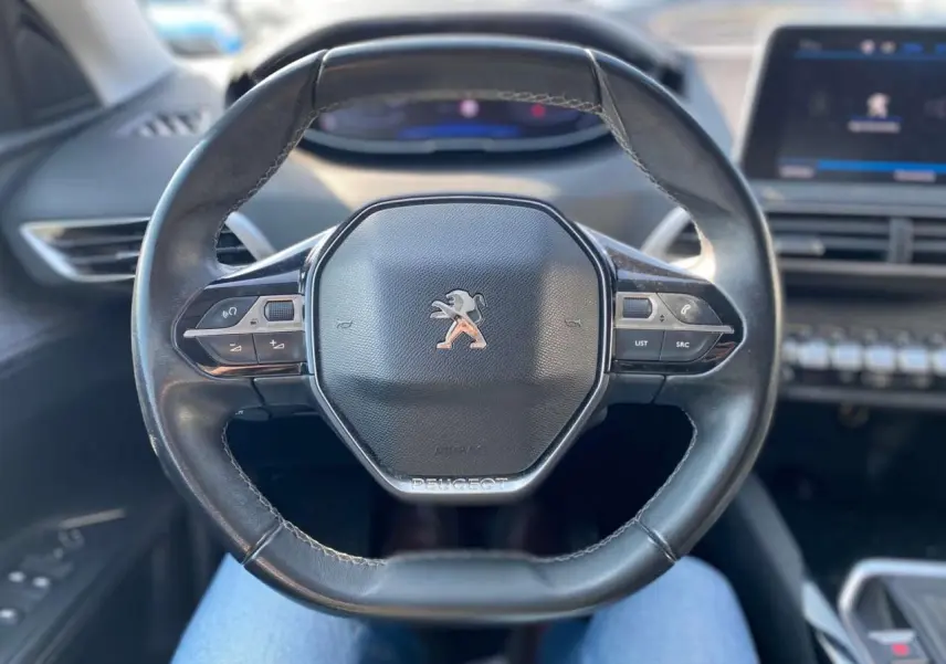 Volant en cuir noir de Peugeot 3008 2018 vu de face, avec commandes intégrées et tableau de bord flou en arrière-plan.