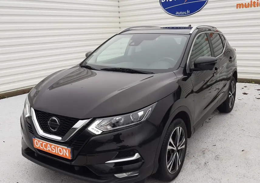 Vue 3/4 avant droit d'un Nissan Qashqai noir 2020 avec jantes alliage et calandre chromée, stationné devant un mur blanc.