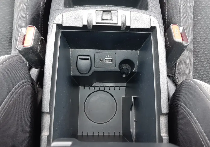 Vue plongeante sur le rangement central noir du Nissan Qashqai 2020, avec prise USB et porte-gobelet visible.