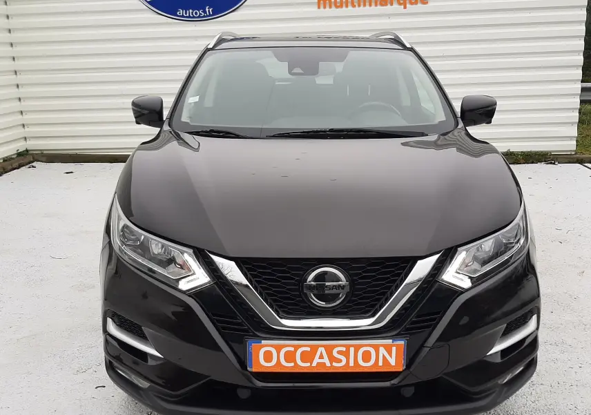 Vue de face d'un Nissan Qashqai noir 2020 avec plaque "OCCASION" et calandre chromée, devant un mur blanc marqué Distinxion.