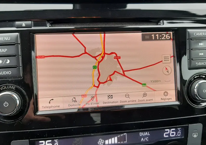 Vue rapprochée de l’écran tactile du système de navigation du Nissan Qashqai noir, affichant une carte routière et les commandes de climatisation.