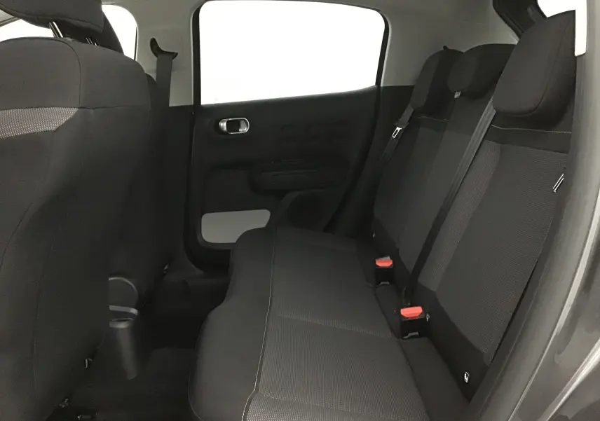 Vue intérieure sur les sièges arrière noirs de la Citroën C3 2022, avec ceinture de sécurité et porte côté gauche visible.