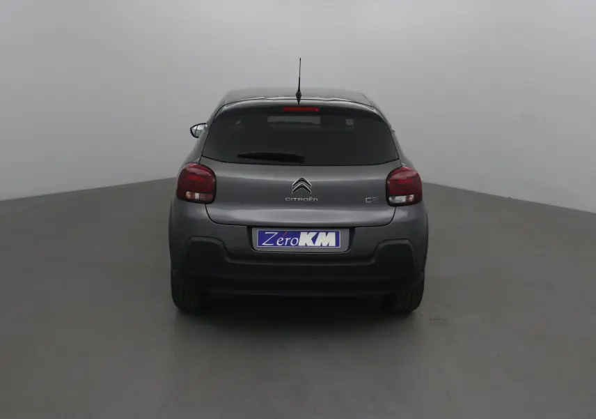 Vue arrière d'une Citroën C3 2022 gris platinium avec feux arrière rouges et plaque Zero KM visible