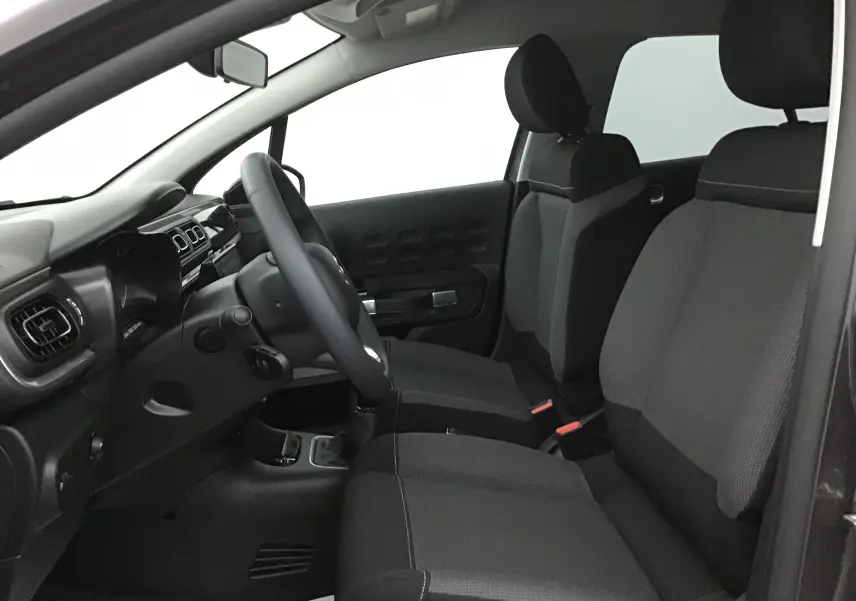 Intérieur de la Citroën C3 2022 vu côté conducteur, sièges tissu gris et tableau de bord noir épuré.
