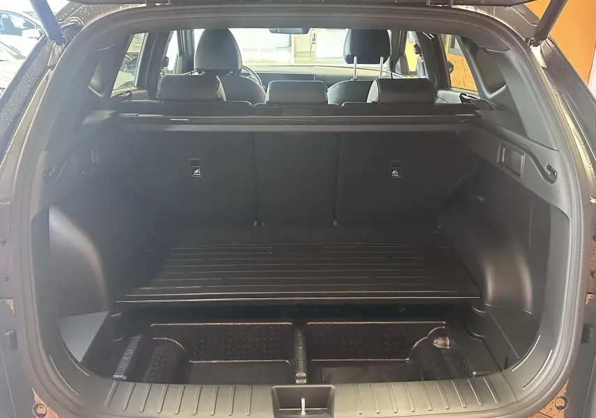 Vue rapprochée de la console centrale du Hyundai Tucson 2025, avec éclairage bleu et commandes tactiles noires.