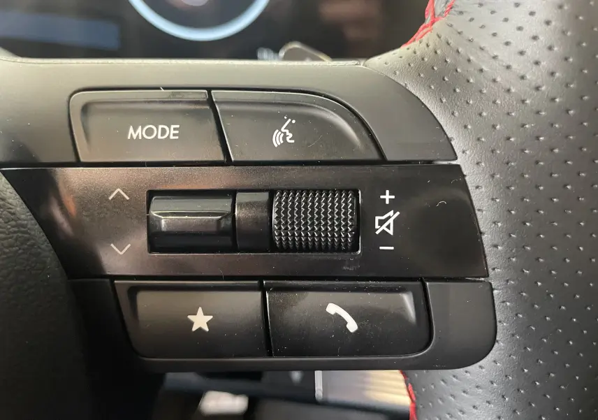 Vue intérieure côté conducteur du Hyundai Tucson gris Ecotronic 2025, sièges noirs avec surpiqûres rouges et tableau de bord digital.