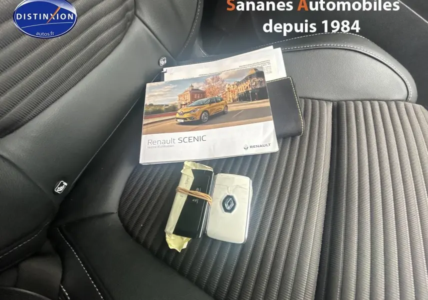 Vue rapprochée de la sellerie noire du Renault Scenic 2020 avec clés et notice d'utilisation posées dessus.