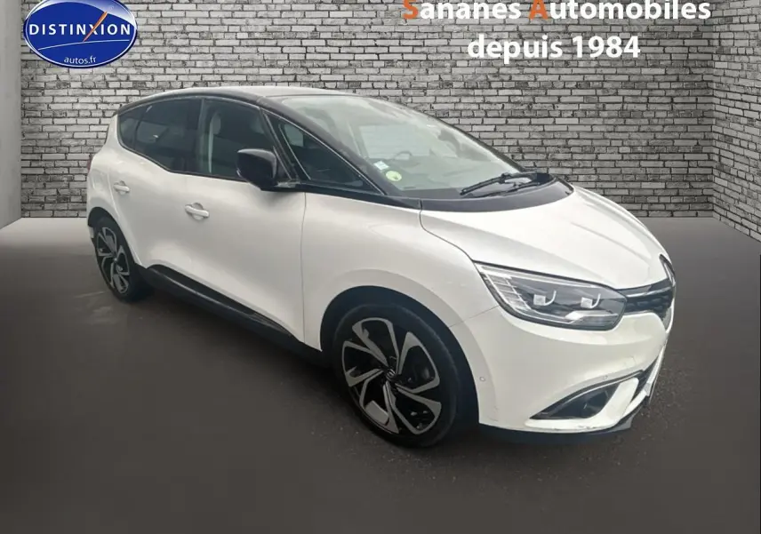Renault Scénic blanc nacré en 3/4 avant droit, toit noir étoilé et jantes alliage 20 pouces distinctives.