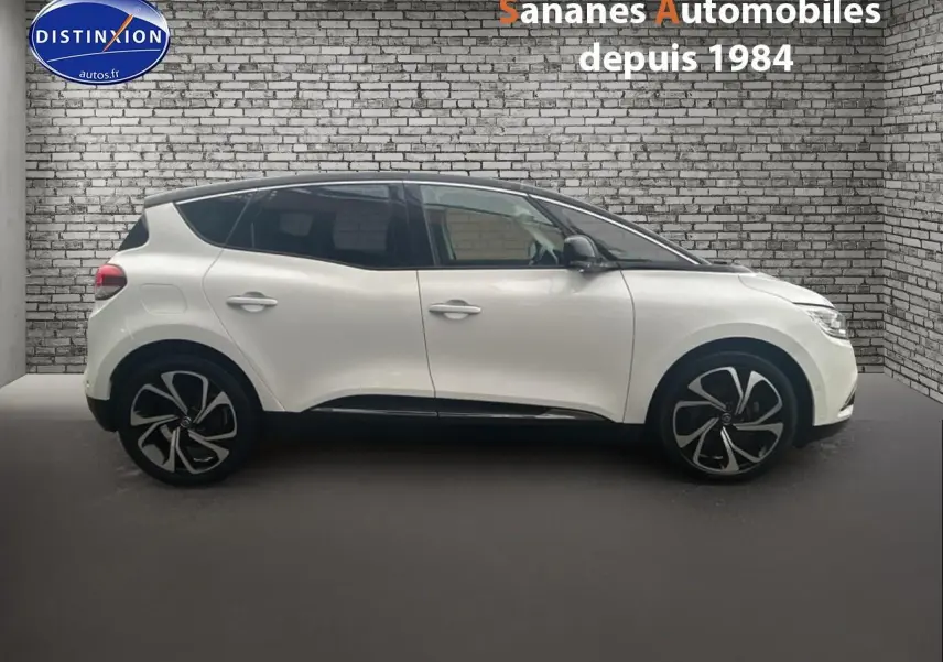 Profil droit d'un Renault Scénic blanc nacré avec toit noir étoilé et jantes alliage 20 pouces dans un showroom.