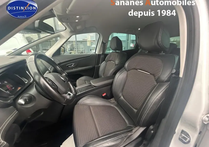 Vue intérieure côté conducteur du Renault Scenic blanc 2020, mettant en valeur les sièges en cuir noir et le volant.