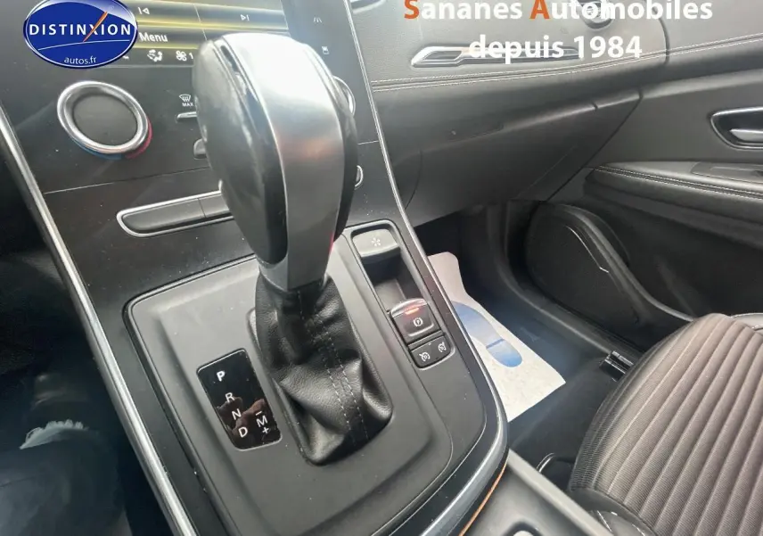 Gros plan sur la console centrale et levier de vitesse automatique du Renault Scénic blanc, intérieur noir avec sellerie tissu.