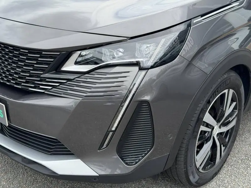 Gros plan sur l'avant droit du Peugeot 3008 Gris Platinium 2024, mettant en valeur le phare et la calandre distinctive.