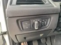 Gros plan sur les commandes d'éclairage à gauche du volant d'une BMW Série 1 blanche 114d M Sport de 2018.