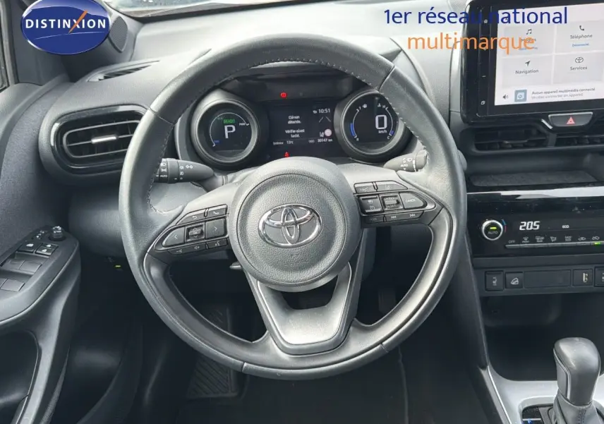 Vue intérieure centrée sur le volant et tableau de bord de la Toyota Yaris Cross gris minéral, avec écran tactile et commandes intégrées.
