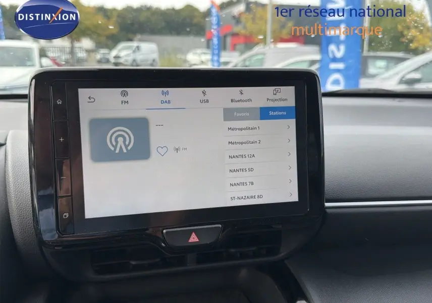 Écran tactile central du Toyota Yaris Cross gris minéral, affichant les options radio DAB en extérieur jour.