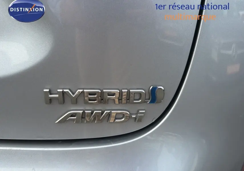 Gros plan sur l'emblème Hybrid AWD-i argenté sur la carrosserie gris minéral d'une Toyota Yaris Cross 2023.