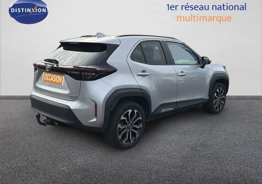 Toyota Yaris Cross gris minéral vue 3/4 arrière droit avec jantes bi-ton et attelage visible.