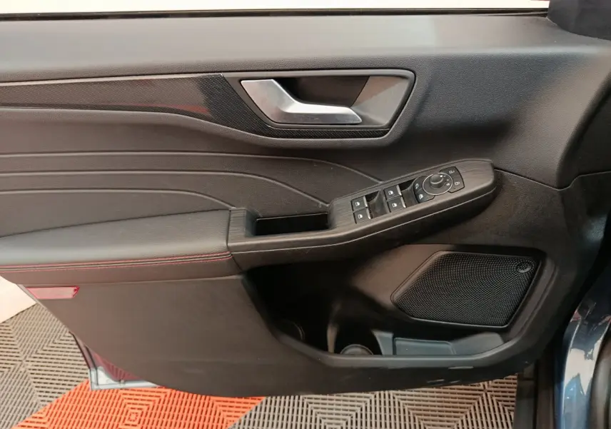 Vue rapprochée de la porte avant gauche du Ford Kuga bleu, avec commandes électriques et garniture noire.