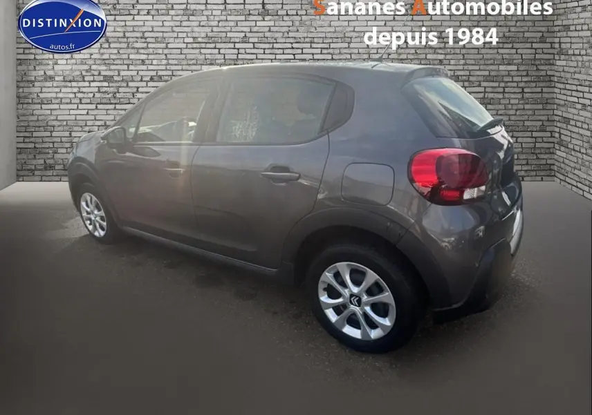 Citroën C3 gris foncé vue 3/4 arrière côté droit, avec jantes alliage et feux arrière arrondis.