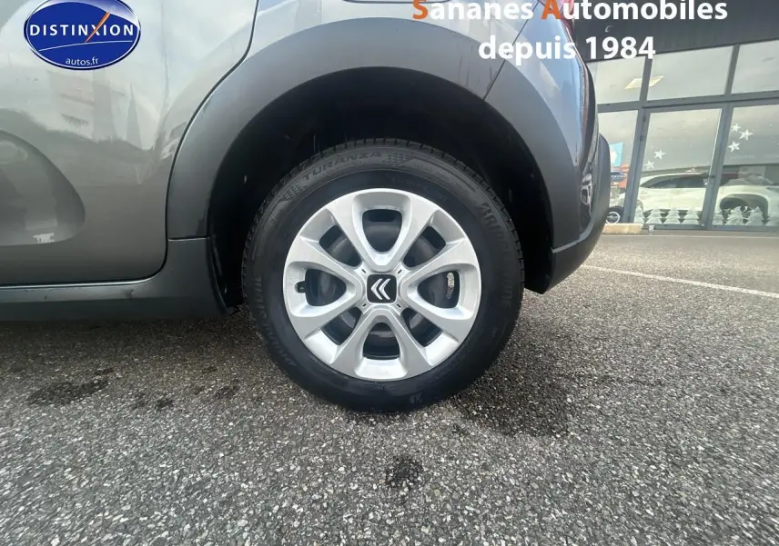 Gros plan sur la roue arrière droite d'une Citroën C3 gris foncé 2023 avec jante alliage et logo Citroën visible.