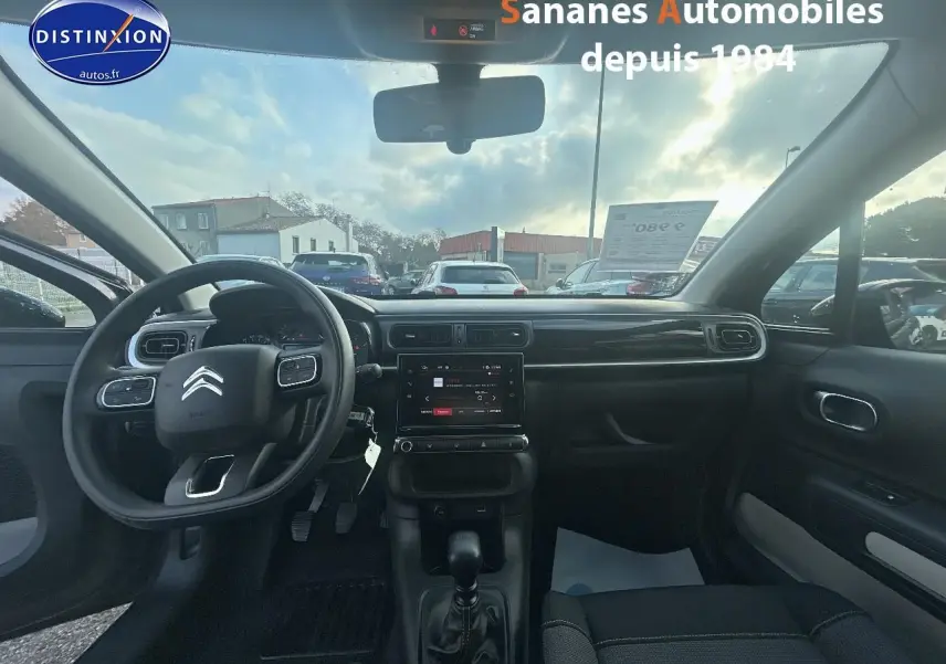 Vue intérieure avant de la Citroën C3 2023 gris foncé, volant multifonction et écran tactile central visible.