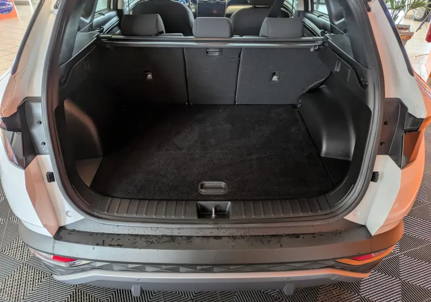 Coffre ouvert vu de l'arrière d'un Hyundai Tucson blanc 2021, montrant un espace de chargement propre et spacieux.