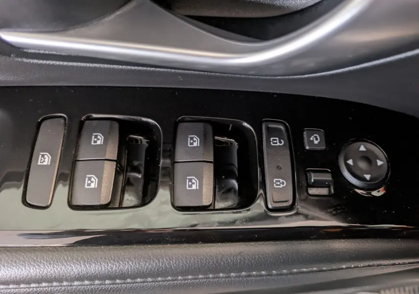 Détail des commandes de lève-vitres et rétroviseurs sur la porte côté conducteur d'un Hyundai Tucson blanc 2021.