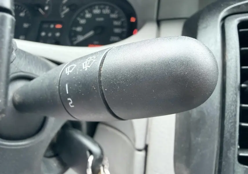 Gros plan sur la manette d’essuie-glace du tableau de bord intérieur d’un Nissan Primastar blanc de 2005.