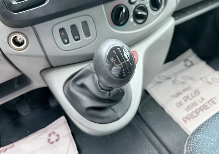 Gros plan sur le levier de vitesses manuel noir dans l’habitacle gris clair du Nissan Primastar blanc.