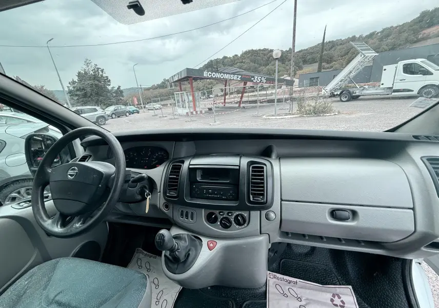Vue intérieure du tableau de bord gris bleu et volant cuir du Nissan Primastar 2005 côté conducteur.