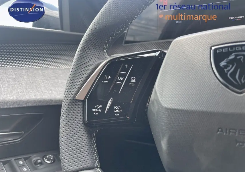 Gros plan sur le volant perforé et les commandes multifonctions du Peugeot 5008 HYBRID noir métal, intérieur moderne.