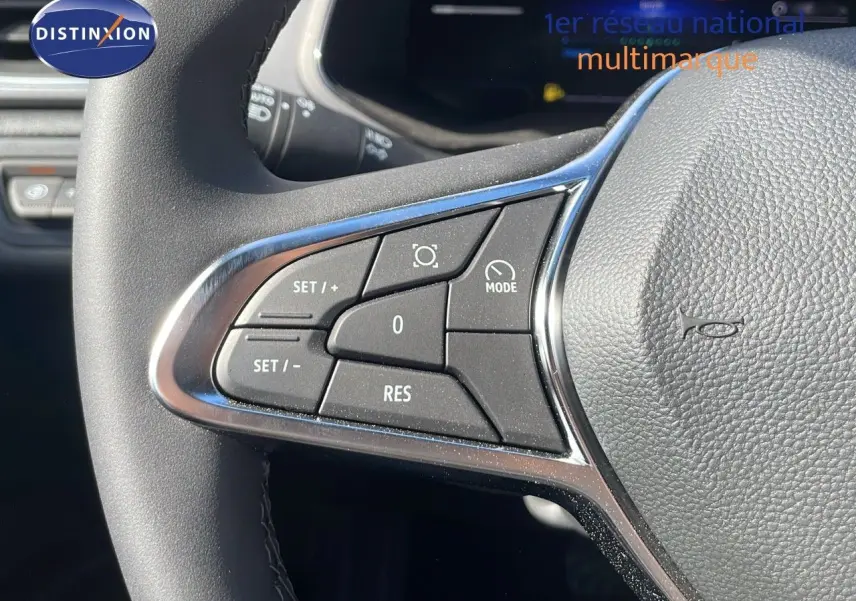 Gros plan sur les commandes du volant à gauche du Renault Captur noir étoile métal avec toit gris, version hybride 2025.