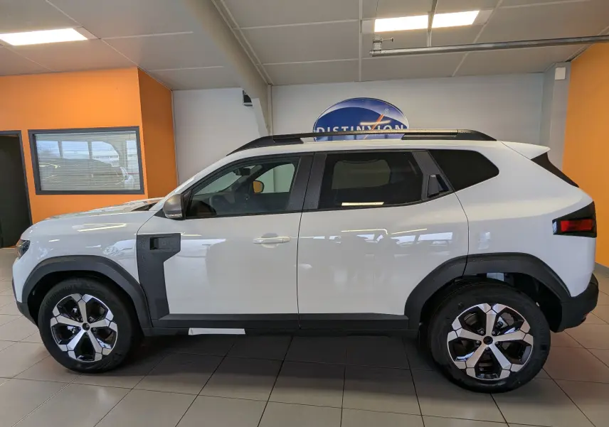 Vue de profil côté gauche du Dacia Duster Hybrid 140 Journey blanc glacier avec jantes alliage 18 pouces bicolores.