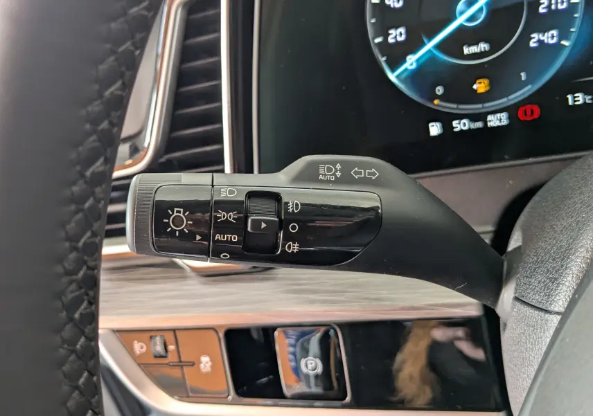 Gros plan sur la commande des phares et clignotants à gauche du volant du Kia Sportage 2025, intérieur noir et bois clair.