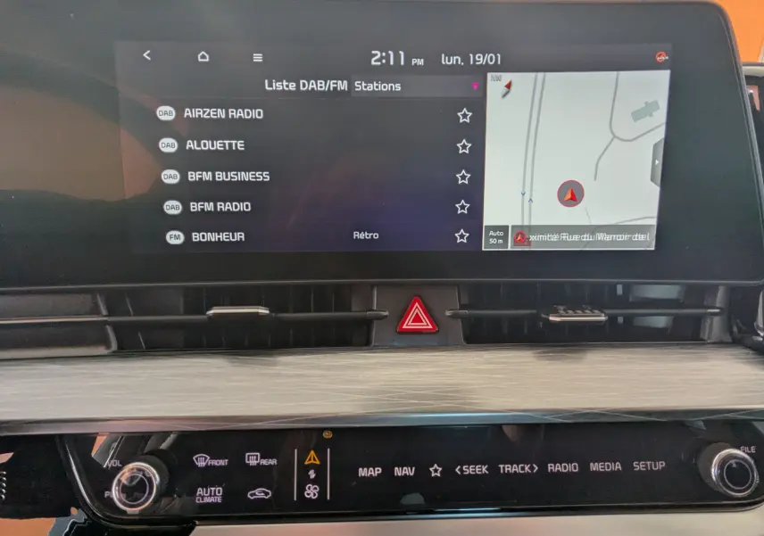 Écran tactile 12,3’’ du système de navigation Kia Sportage 2025, affichant liste radio DAB et carte GPS.