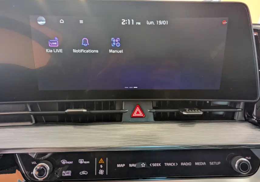 Écran tactile 12,3’’ du système de navigation Kia avec commandes multimédia et bouton de signalisation au centre.